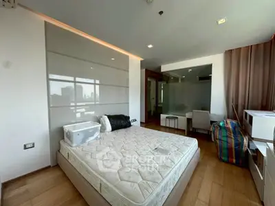 Spacious bedroom with modern design and city view, featuring hardwood floors and ample natural light.