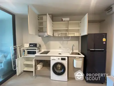 Modern kitchen with appliances including washing machine and fridge in compact layout