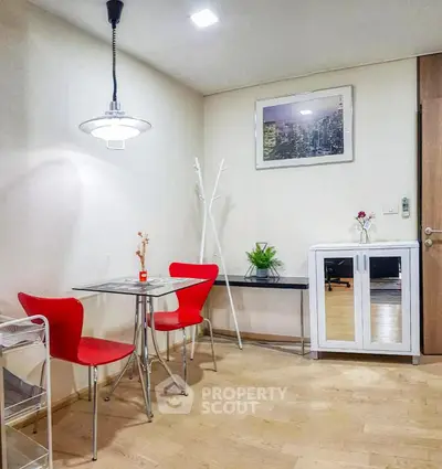 Modern dining area with red chairs and glass table in a stylish apartment.