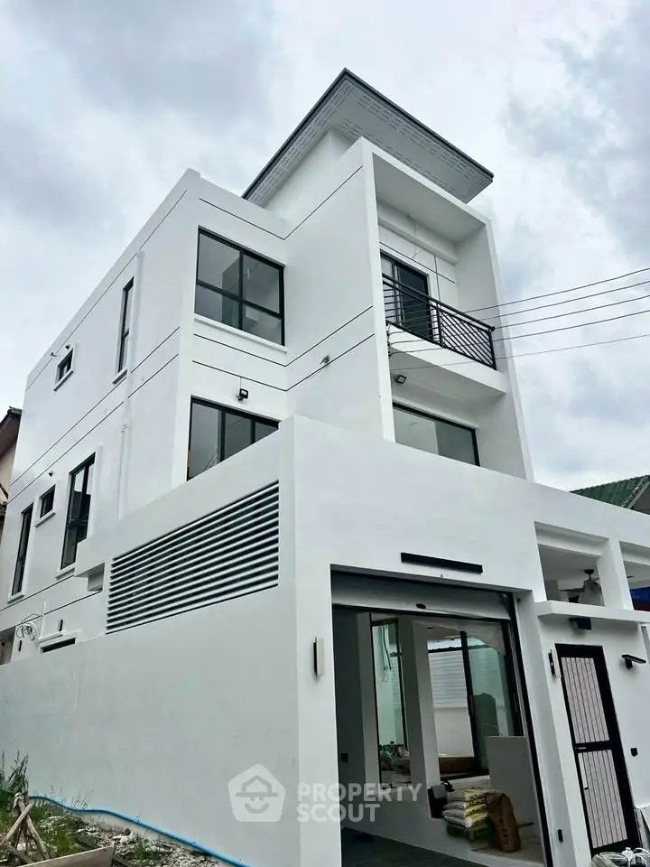 Modern three-story white house with sleek design and large windows, showcasing contemporary architecture.