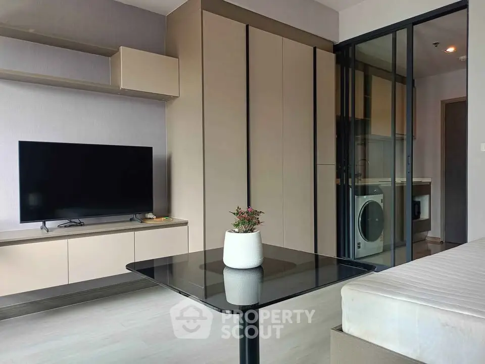 Modern living room with sleek furniture and integrated kitchen appliances in a stylish apartment.