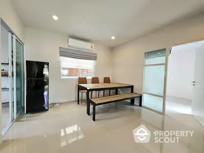 Modern dining area with sleek table and chairs, adjacent to a stylish kitchen and large window.