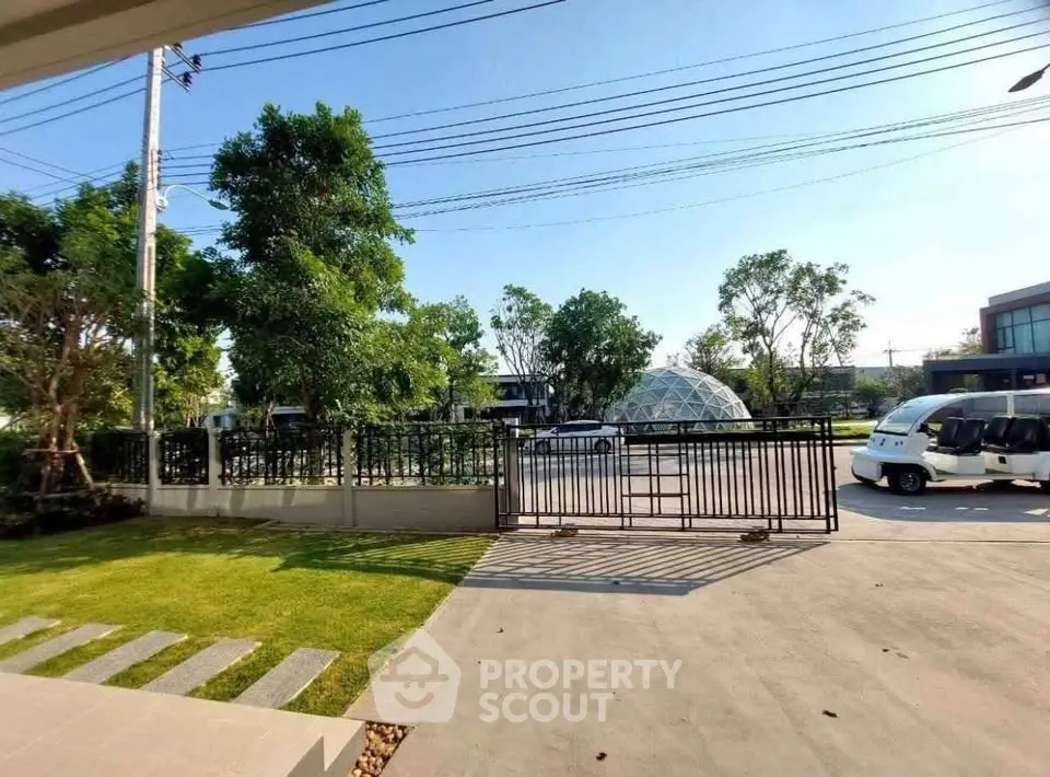 Spacious driveway with lush greenery and modern gate in a serene neighborhood.