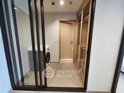 Modern laundry area with sliding glass doors and wooden cabinetry in a stylish apartment.