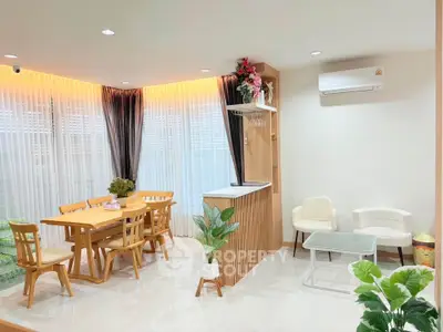 Modern living room with dining area, featuring elegant wooden furniture and bright natural lighting.