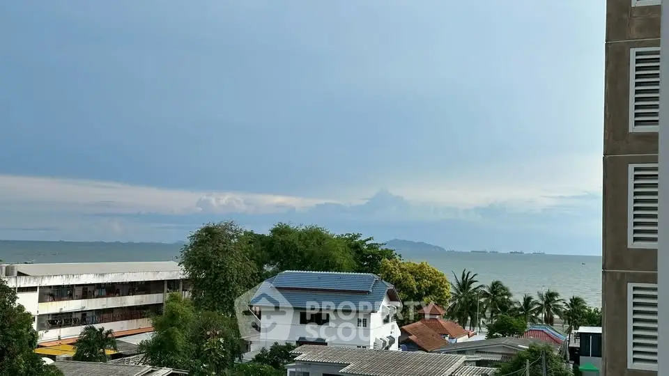 Stunning ocean view from a high-rise building overlooking lush greenery and rooftops.