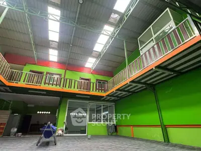 Spacious industrial-style interior with vibrant green walls and high ceilings, perfect for creative workspace.