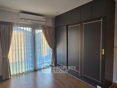 Modern bedroom with large wardrobe and natural light from balcony window.