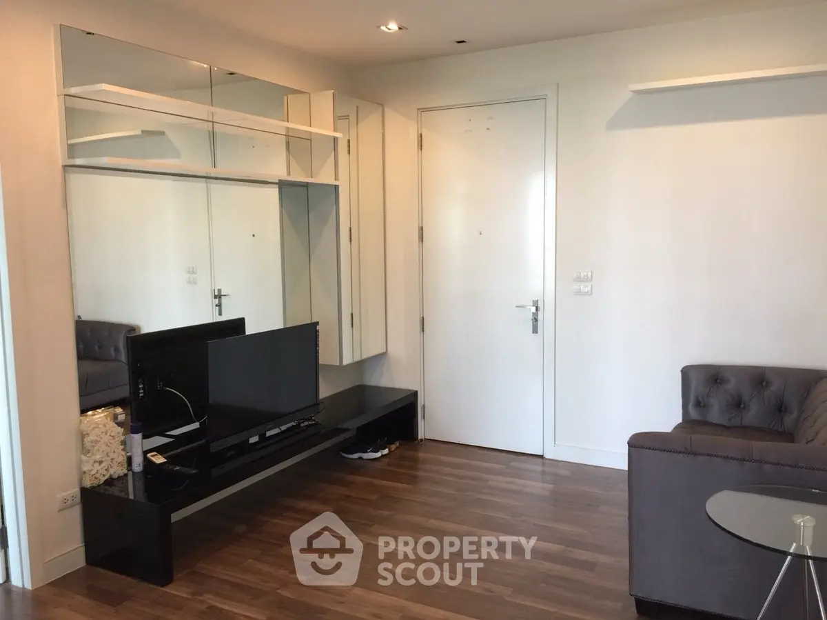 Modern living room with sleek furniture and wooden flooring, featuring a wall-mounted TV and stylish decor.