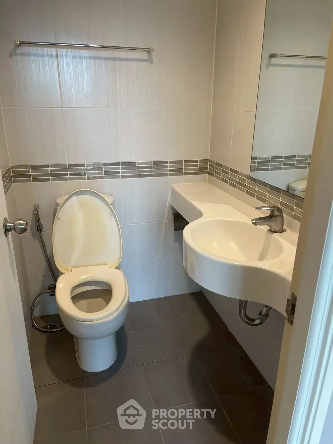 Modern bathroom with sleek fixtures and contemporary design, featuring a wall-mounted sink and tiled walls.