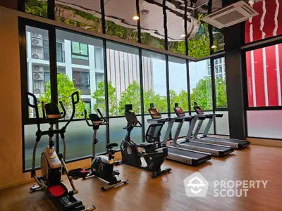 Modern gym with cardio equipment and large windows in luxury apartment building