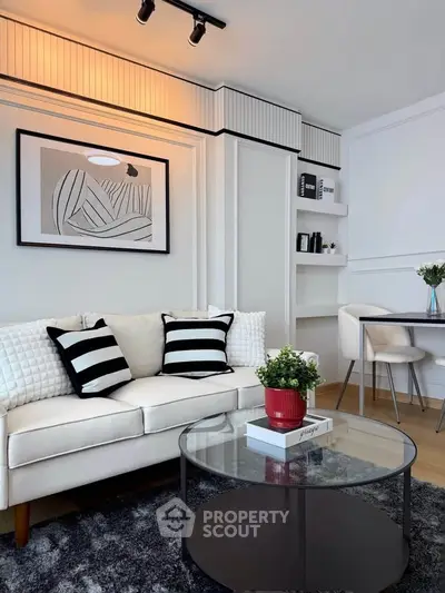Modern living room with stylish decor, featuring a cozy white sofa, glass coffee table, and elegant wall art.