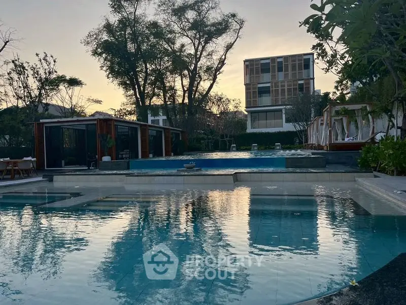 Luxurious residential pool area with modern architecture and serene surroundings at sunset.