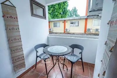 Charming balcony with cozy seating and view of neighboring buildings, perfect for relaxation.