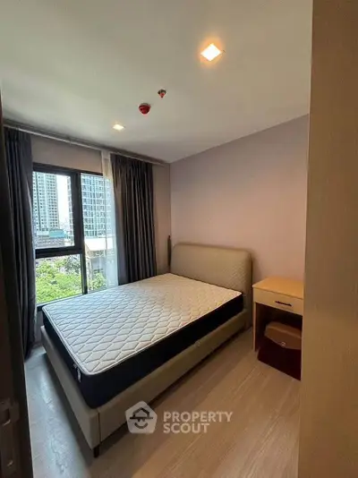 Modern bedroom with large window and city view, featuring a comfortable bed and sleek design.
