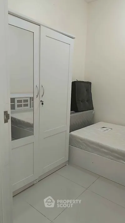 Cozy bedroom with white wardrobe and single bed, perfect for minimalist living.