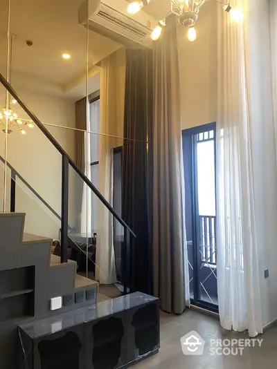 Elegant two-story living space with modern staircase, high ceilings, and chic chandelier, leading to a sunlit balcony with sheer curtains.