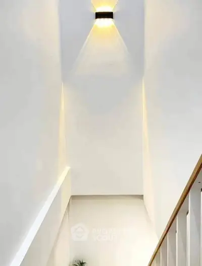 Minimalist staircase with modern wall light in a bright, airy home interior.