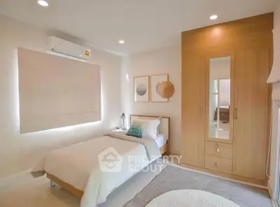 Cozy bedroom with modern decor, featuring a single bed, built-in wardrobe, and soft lighting.