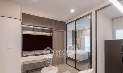 Modern apartment interior with open living room and bedroom view, featuring sleek design and natural lighting.