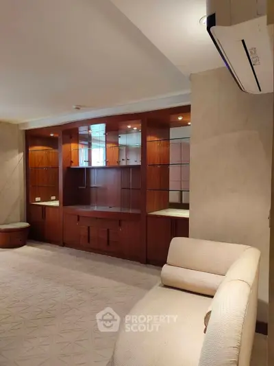 Spacious living room with elegant built-in wooden cabinets and modern air conditioning.