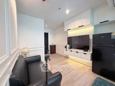 Modern living room with sleek black sofa, wall-mounted TV, and contemporary decor.