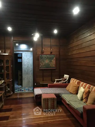 Cozy living room with wooden walls and warm lighting, featuring a comfortable sofa and decorative elements.