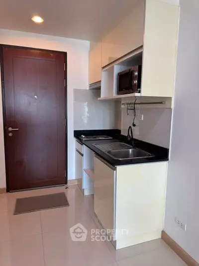 Compact modern kitchen with sleek cabinetry and stainless steel sink in a cozy apartment.