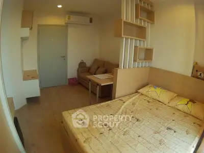 Cozy bedroom with modern decor and wooden flooring, featuring a small seating area and air conditioning.