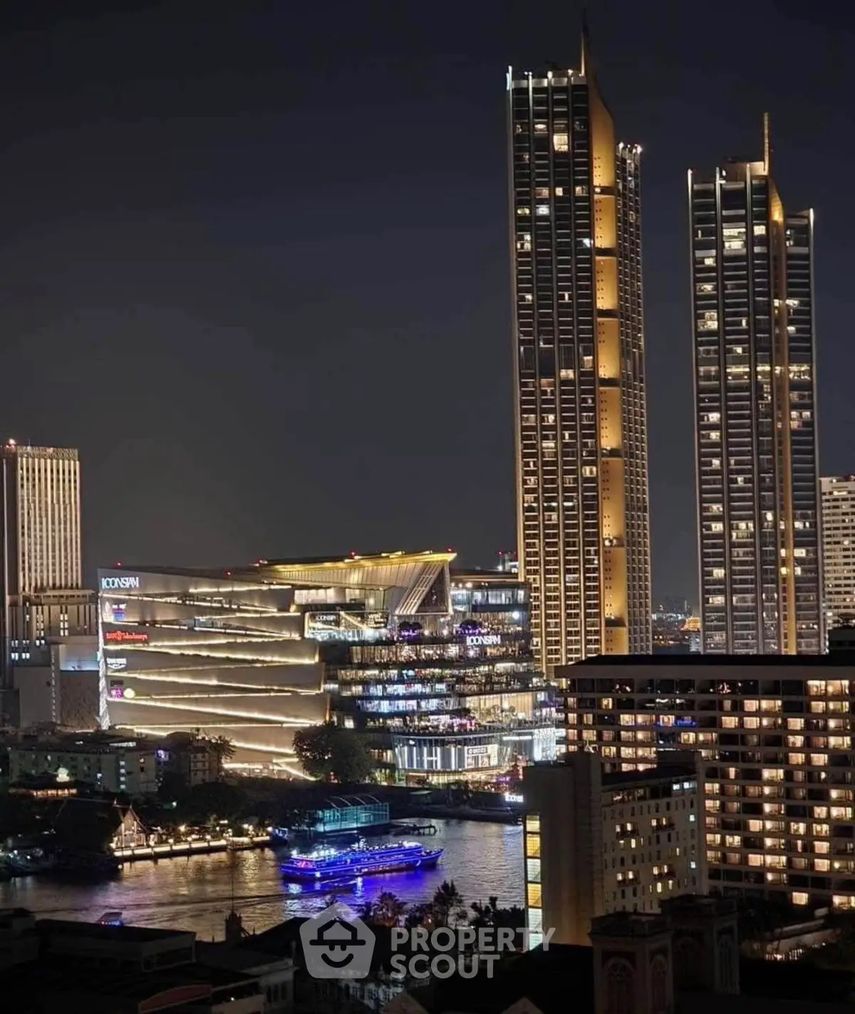 Stunning night view of illuminated skyscrapers by the river, showcasing modern urban architecture.