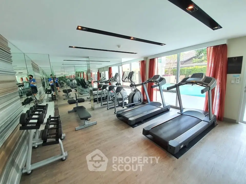 Modern gym with state-of-the-art equipment and pool view in luxury residential complex.
