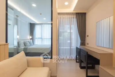 Modern bedroom with glass partition and cozy seating area, featuring elegant curtains and ambient lighting.