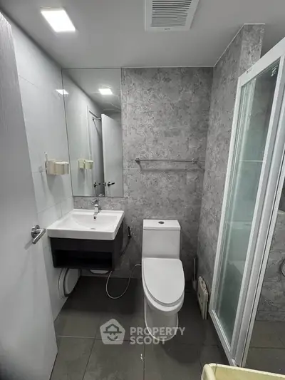 Modern bathroom with sleek fixtures and glass shower enclosure in a contemporary apartment.