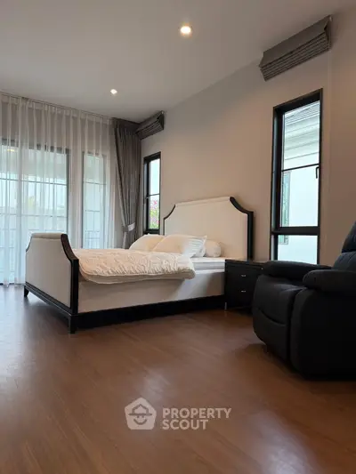 Spacious modern bedroom with elegant decor and large windows for natural light.