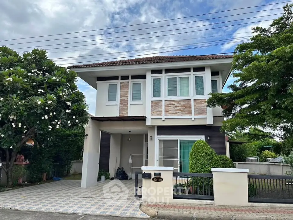 Charming two-story house with modern facade and lush greenery in serene neighborhood.