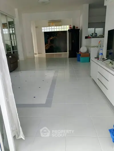 Spacious open-plan living area with modern white tiles and ample natural light.