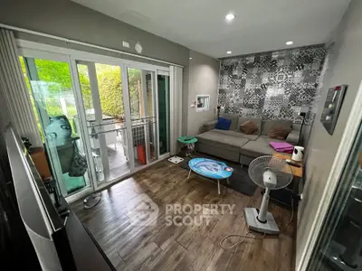 Cozy living room with modern decor and sliding glass doors to a lush garden balcony.