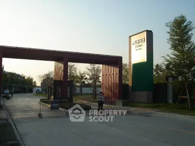 Modern gated community entrance with security and lush greenery