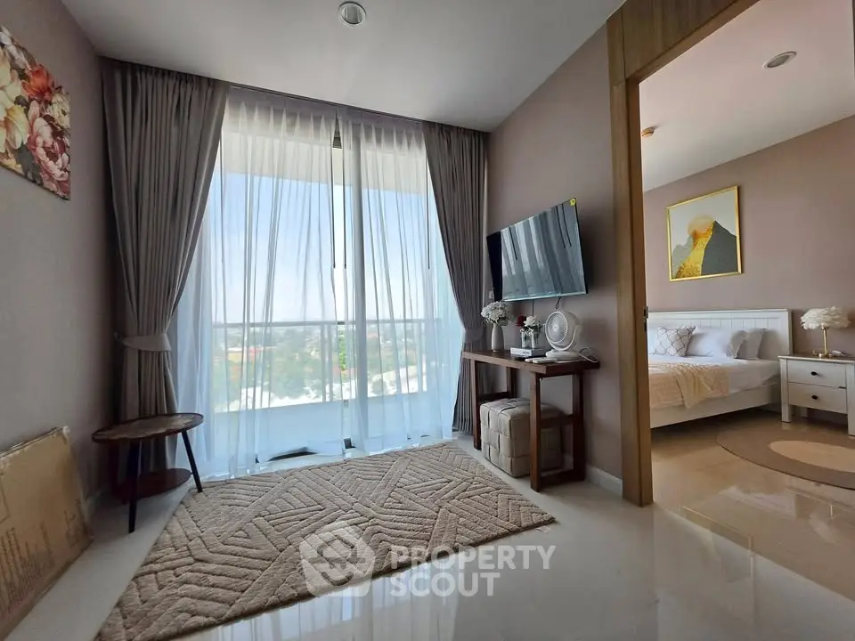 Modern living room with large window and bedroom view, featuring elegant decor and natural light.