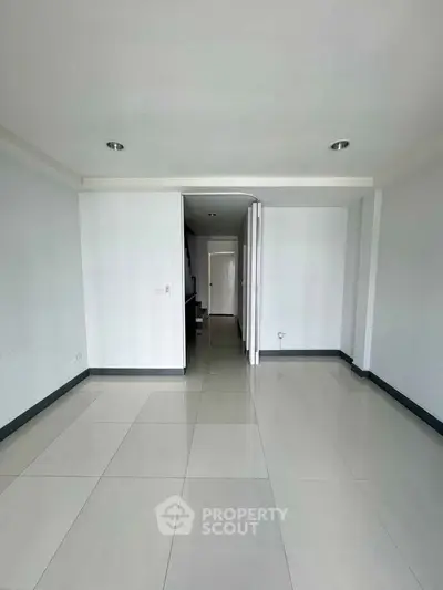 Spacious empty room with glossy tiled flooring and recessed lighting, ideal for customization.
