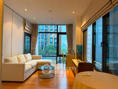 Spacious modern living room with large windows and city view, featuring elegant furniture and natural light.