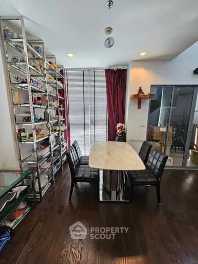 Modern dining area with sleek table, chairs, and floor-to-ceiling shelves in a stylish home interior.