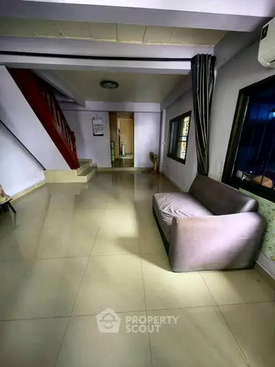 Spacious living room with modern sofa and staircase, ideal for family gatherings.