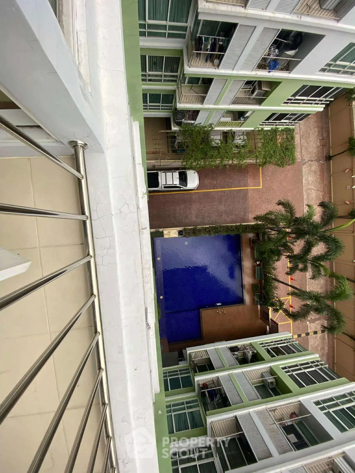 Stunning aerial view of modern apartment complex with pool and lush greenery.