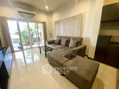 Spacious living room with modern sofa and large glass doors opening to a balcony.