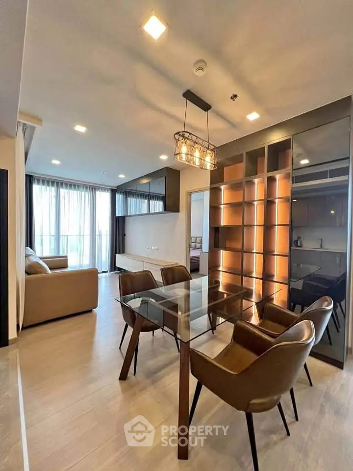 Modern living room with glass dining table and leather chairs, featuring elegant lighting and spacious design.