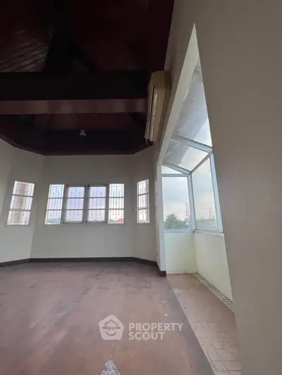 Spacious room with large windows and wooden flooring, perfect for a bright living area.