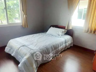 Cozy bedroom with natural light and wooden flooring, perfect for relaxation.