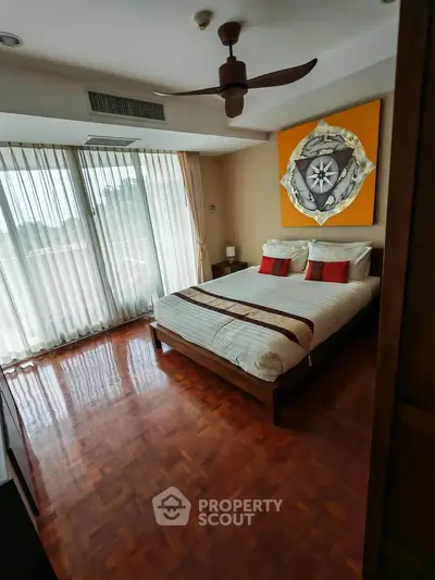 Spacious bedroom with large windows and elegant decor in a modern apartment.