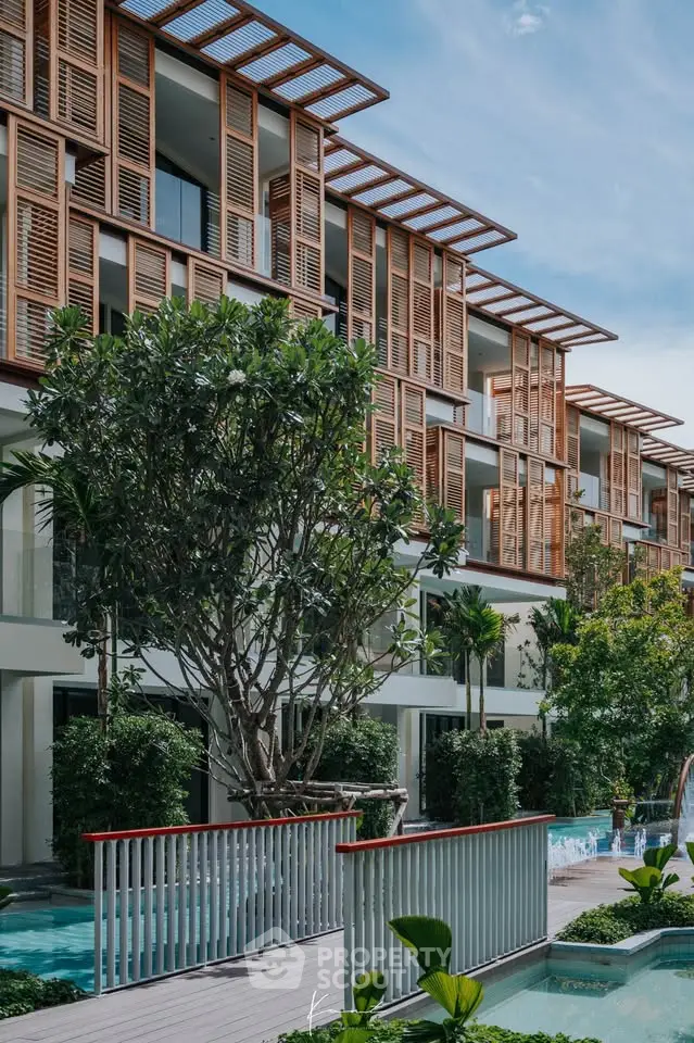 Luxurious modern apartment building with lush greenery and poolside view, perfect for upscale living.